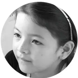 Fotografía circular en blanco y negro de una niña pensando, con cabello recogido y cinta.