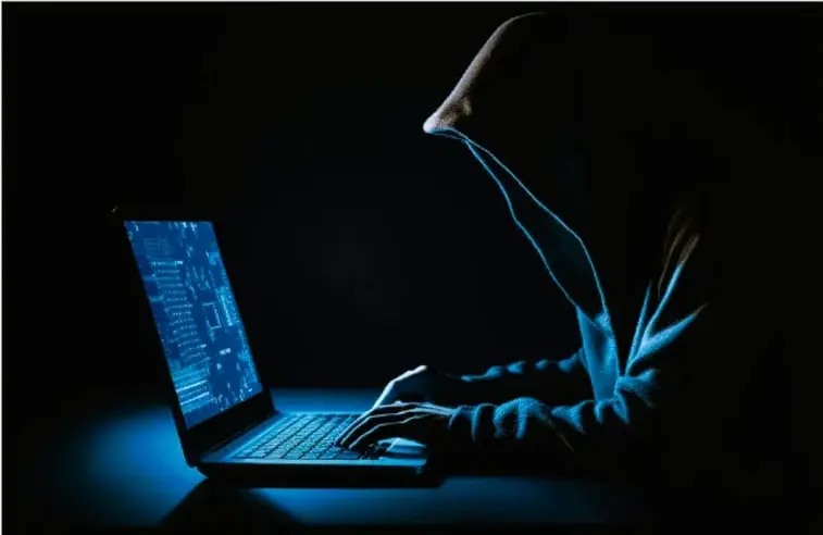 Fotografía de una persona usando un laptop en la oscuridad, iluminada por la pantalla azul, con proyección de símbolos y datos digitales, representando el uso nocturno de redes sociales.