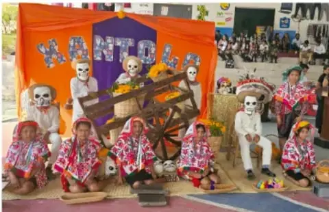 Fotografía de estudiantes con maquillaje de calavera y trajes típicos en una muestra escolar con el letrero «MANTON...», que ilustra la pieza teatral del proyecto.