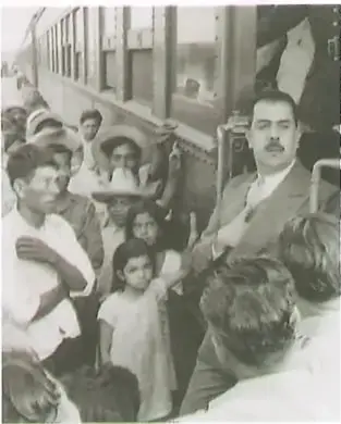 Fotografía histórica en blanco y negro de una multitud reunida alrededor de un vehículo.