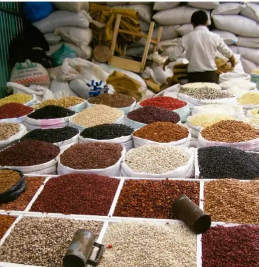 Mercado con granos y semillas en bolsas, ilustrando la vida comunitaria y el uso cotidiano de números.