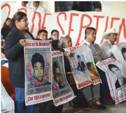 Fotografía de una mujer sosteniendo un cartel con la foto de un joven desaparecido y la leyenda 'Vivo se lo llevaron'.