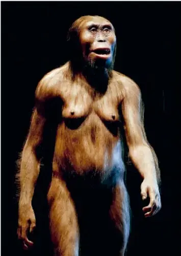 Recreación de un hombre prehistórico de pie, con rasgos faciales y corporales, cubierto con pieles.