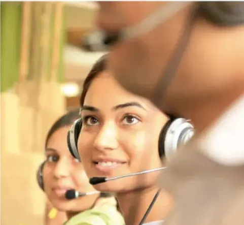 Fotografía de mujeres jóvenes con audífonos trabajando en un centro de atención telefónica, ilustrando el empleo bilingüe mencionado en el texto.