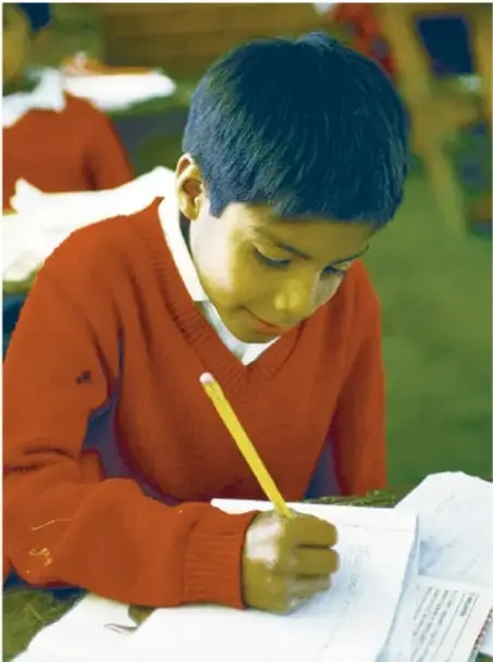 Estudiante con suéter rojo escribiendo en un cuaderno con lápiz amarillo.