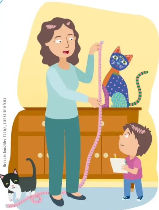 Madre midiendo con un flexómetro un gato de juguete de colores que está sobre un mueble, mientras su hijo pequeño toma notas en un cuaderno; un gato blanco y negro observa la escena.
