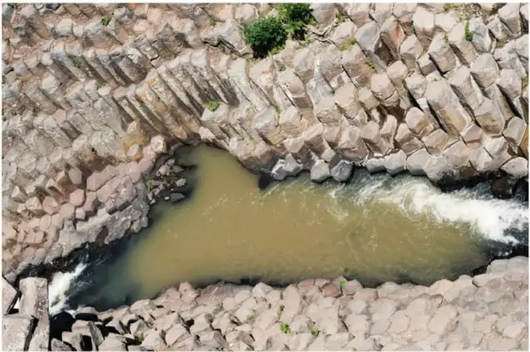 Fotografía aérea de un cañón con columnas de basalto (prismas basálticos) y un río de agua turbia en la base, en Huasca de Ocampo, Hidalgo.