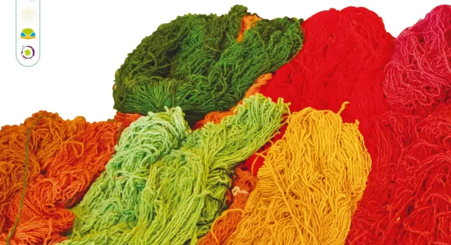 Fotografía de montones de madejas de estambre o lana teñida en colores brillantes: rojo, magenta, naranja, amarillo, verde claro, verde oscuro y tonos turquesa.