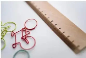 Clips de colores junto a una regla graduada de madera.