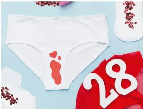 Ropa interior blanca con una marca roja, un número 28 y flores, relacionada con el ciclo menstrual.