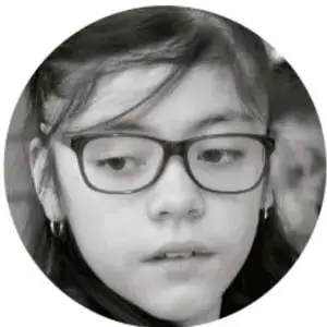 Fotografía de una estudiante con lentes mirando hacia el frente.