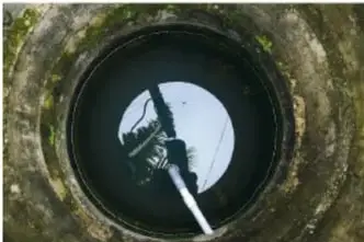 Fotografía de una noria o rueda hidráulica de madera junto a un río.