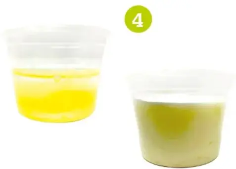 Mano vertiendo jugo de limón en un vaso con leche.