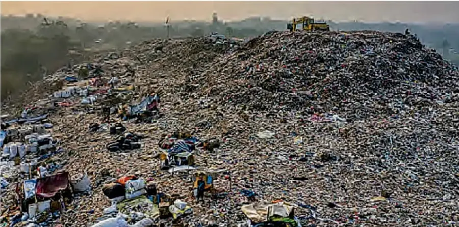 Fotografía de un gran tiradero de basura a cielo abierto con personas trabajando entre los desechos y una ciudad al fondo, que ilustra el impacto de las acciones humanas en el ambiente.