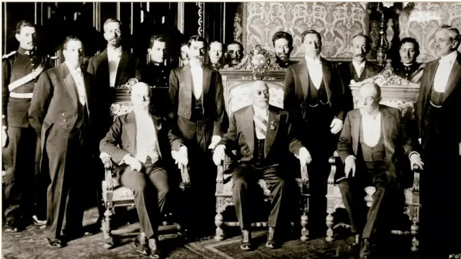 Fotografía histórica del Gabinete de Victoriano Huerta, 1913. Biblioteca del Congreso de Estados Unidos; grupo de hombres con trajes formales y uniformes posando en un salón.