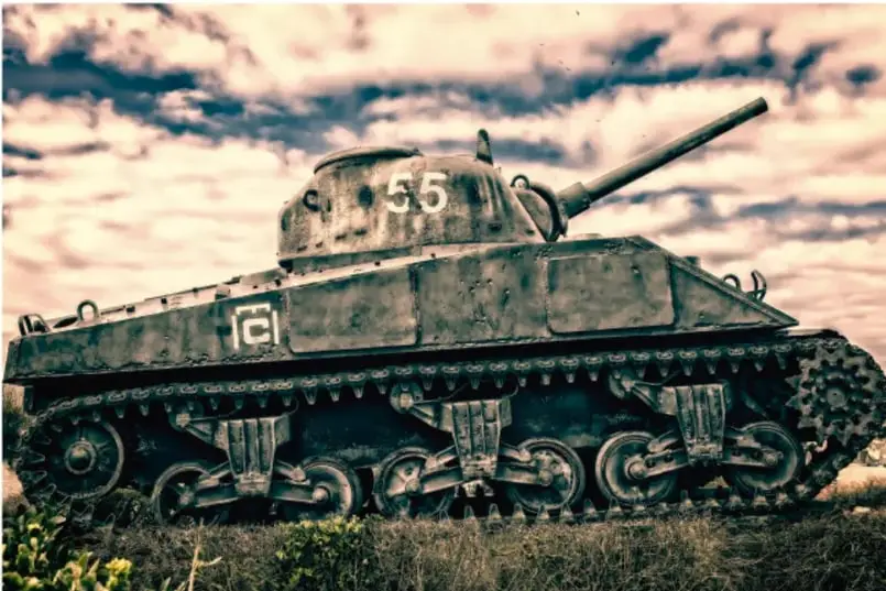 Fotografía de un tanque militar (carro de combate tipo Sherman con el número 55 en la torreta) en un campo con nubes al fondo, ilustrando el tema bélico de la Segunda Guerra Mundial.