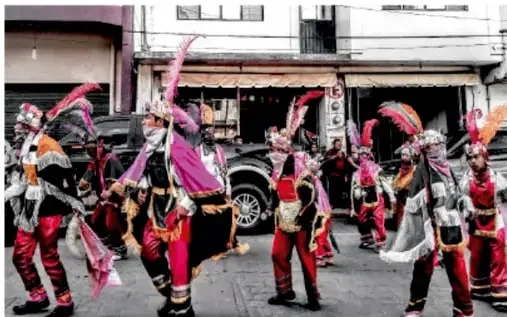 Fotografía de bailadores con trajes coloridos y penachos de plumas en una calle, obra de Rosa Laura Teran Ulite, VERAXUL.
