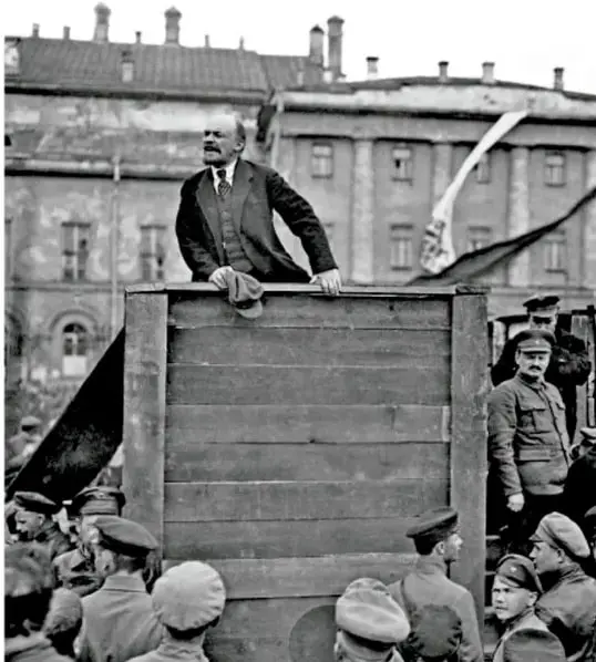 Fotografía histórica en blanco y negro de Vladimir Lenin discurriendo desde una tribuna de madera ante una multitud de soldados y obreros, probablemente durante la Revolución Rusa de 1917.