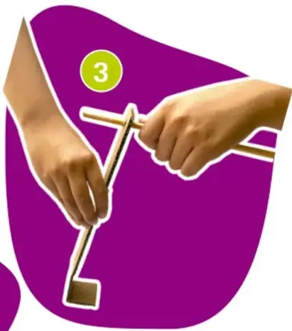Manos perforando una tira de cartón con un palo de madera, paso 3.