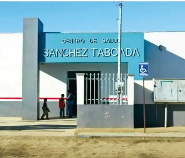 Fotografía de la fachada de un Centro de Salud Sánchez Taboada, con personas en la entrada.