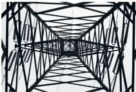 Fotografía en blanco y negro de una torre de transmisión eléctrica vista desde abajo, con líneas que convergen hacia un punto de fuga.