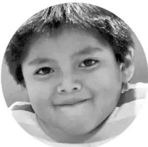 Fotografía circular en escala de grises de un niño de primaria sonriendo a la cámara, ilustrando el escenario escolar.