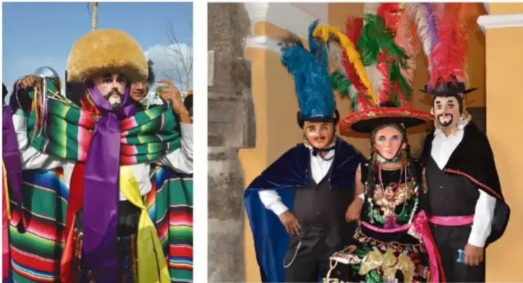 Persona disfrazada con traje de listones de colores, sombrero grande y máscara en una fiesta tradicional.