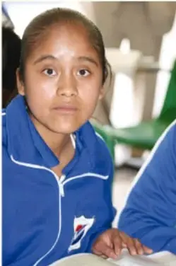 Fotografía de una estudiante con uniforme azul en un salón de clases.