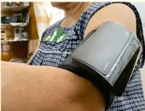 Fotografía de una persona colocándose un baumanómetro digital en el brazo, ejemplo de máquina del campo de la salud.