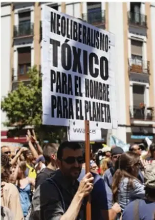 Fotografía de una protesta con una pancarta que dice: 'NEOLIBERALISMO: TÓXICO PARA EL HOMBRE, PARA EL PLANETA'.