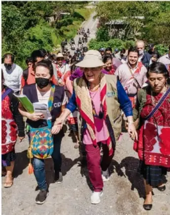 Fotografía de un grupo de personas, en su mayoría mujeres indígenas, caminando por un sendero rural. Algunas portan pancartas y vestimenta tradicional. La imagen ilustra la participación y movilización de grupos marginados en la defensa de sus derechos.