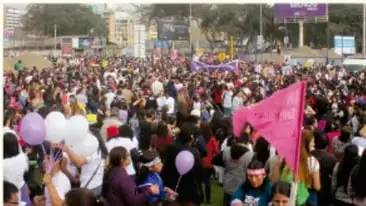 Fotografía de una multitud reunida al aire libre con globos y pancartas, representando una manifestación o foro público.