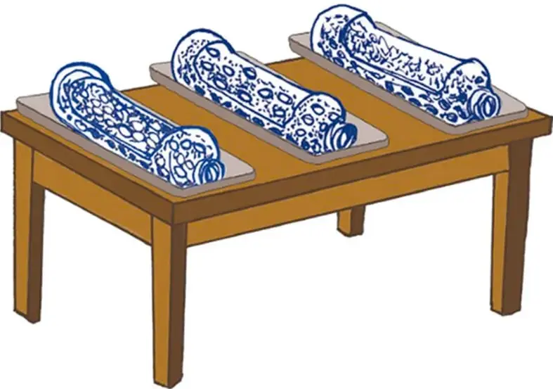 Mesa de madera sobre la que se acomodan tres botellas recortadas, cada una sobre su charola, dentro del aula.