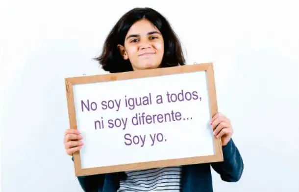 Joven sosteniendo un cartel escrito a mano: «No soy igual a todos, ni soy diferente… Soy yo.»