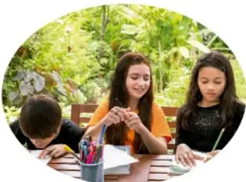 Tres estudiantes sentados en una mesa al aire libre revisan y comentan una infografía.