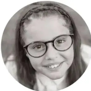 Fotografía de una niña con lentes sonriendo.