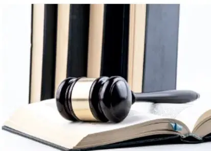 Mazo de juez sobre un libro abierto, junto a libros de derecho, símbolo de justicia y juicio.