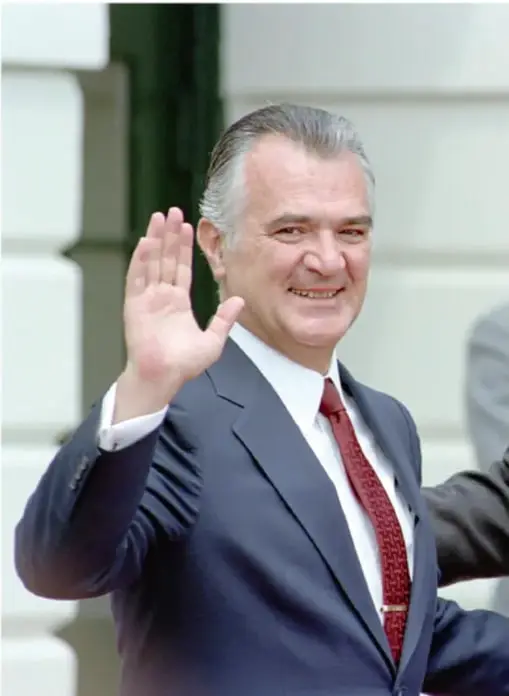 Fotografía de Miguel de la Madrid Hurtado, presidente de México (1982-1988), saludando con la mano derecha, vestido con traje azul y corbata roja.