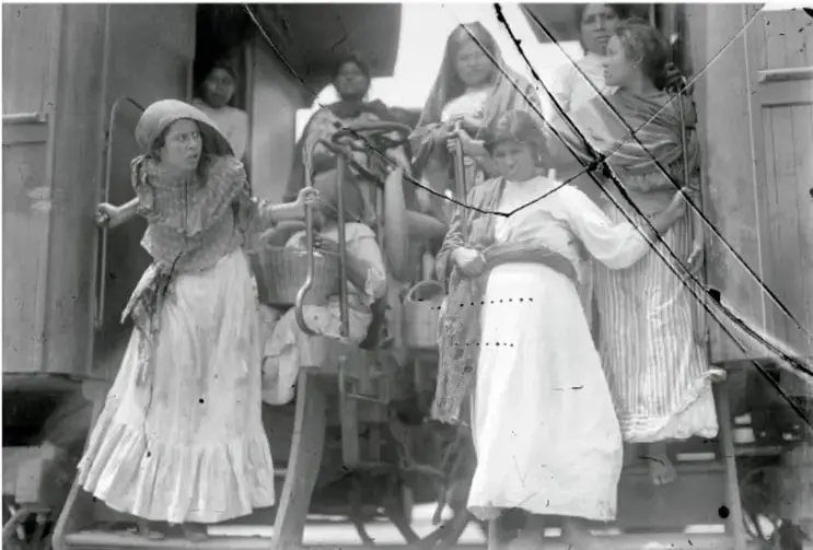 Fotografía en blanco y negro de un grupo de personas, principalmente mujeres con vestimenta de la época, subiendo a un tren durante la Revolución Mexicana.