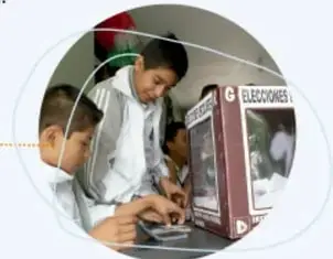 Niños y una niña frente a una urna electoral con el letrero 'ELECCIONES', simbolizando el voto.