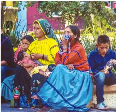 Fotografía de mujeres y niños indígenas de México vestidos con trajes tradicionales.
