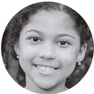 Retrato en blanco y negro de una niña sonriente con el cabello recogido.