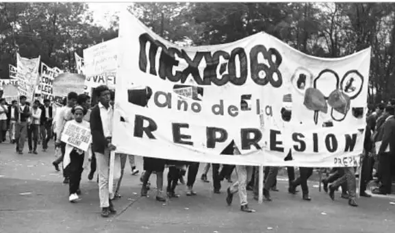 Fotografía de una marcha estudiantil con una manta que dice 'MÉXICO 68 AÑO DE LA REPRESIÓN'.