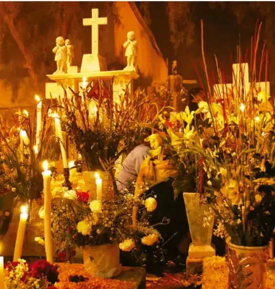 Fotografía de un altar o ceremonia religiosa con velas encendidas, cruces, flores y figuras de santos, ilustrando la convivencia del culto eclesiástico y las tradiciones indígenas.