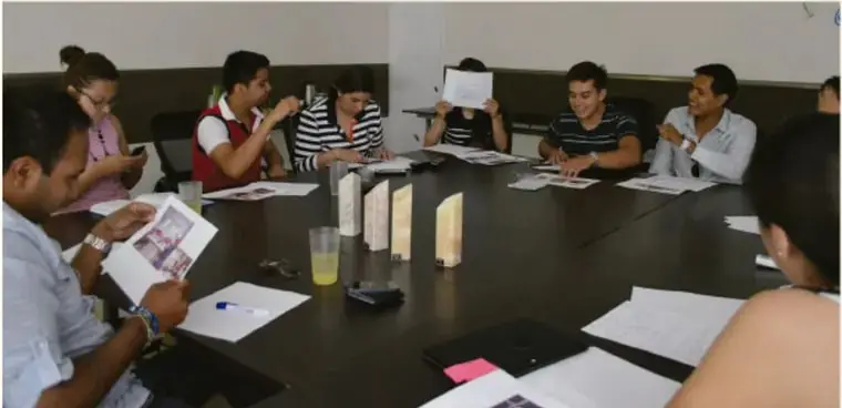 Fotografía de una asamblea escolar: jóvenes sentados alrededor de una mesa revisando hojas y manualitos, crédito Guiemra Rodríguez Acalos: M.E.A.