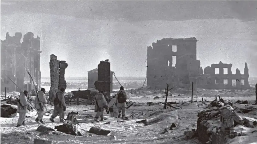 Fotografía en blanco y negro de soldados caminando entre ruinas de una ciudad destruida, probablemente Stalingrado.
