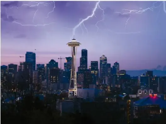 Fotografía nocturna de una ciudad con la Torre Space Needle de Seattle y rayos en el cielo morado.