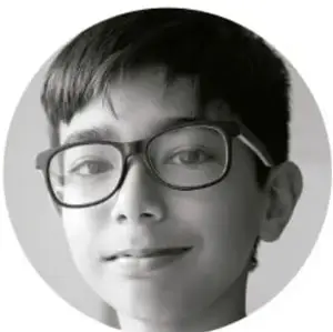 Fotografía en blanco y negro de un niño con lentes que sonríe.