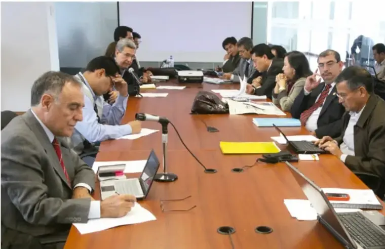 Fotografía de un equipo de trabajo reunido en una mesa larga, con laptops y documentos, colaborando en la elaboración de un plan.