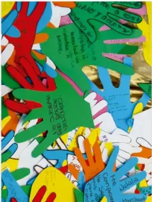 Fotografía de muchas manos recortadas en papel de colores superpuestas, con textos escritos, símbolo de la diversidad.